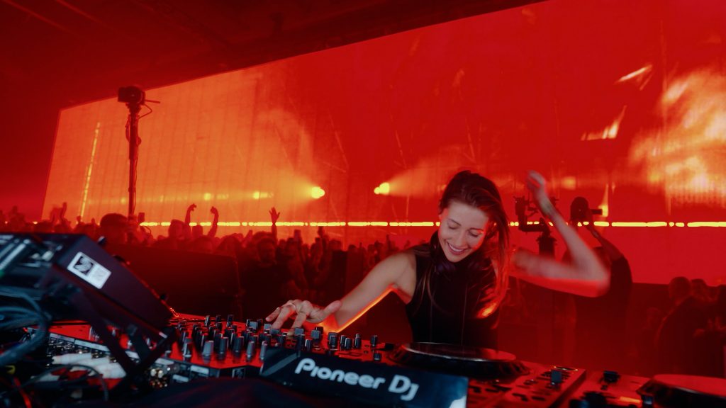 HER SOUND – Charlotte aan de dj-tafel met rode achtergrond