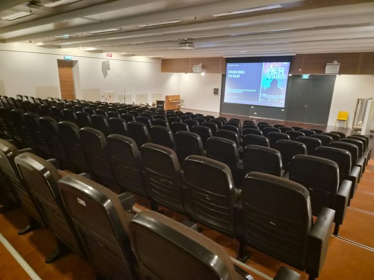 Collegezaal van Inholland met de presentatie voor het gastcollege Creative Business op het scherm.